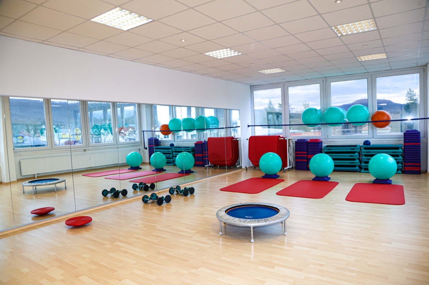 Gymnastikraum mit Spiegelwand, Matten und Gymnastikbällen